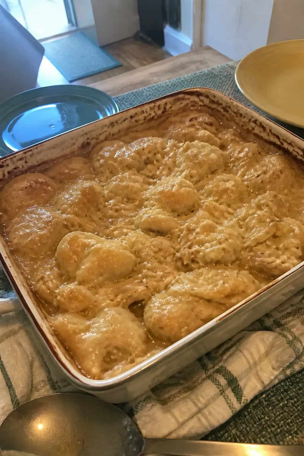 A creamy chicken and dumpling casserole in a rectangular baking dish on a kitchen table.