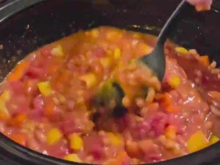 Slow Cooker Pumpkin Lentil Chili with Cinnamon and Nutmeg 5 A spoon stirs the mixed tomatoes, beans, and peppers together in the slow cooker.