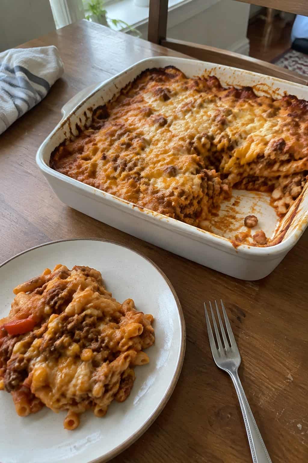 A serving of beef and pasta casserole with melted cheese in a baking dish.