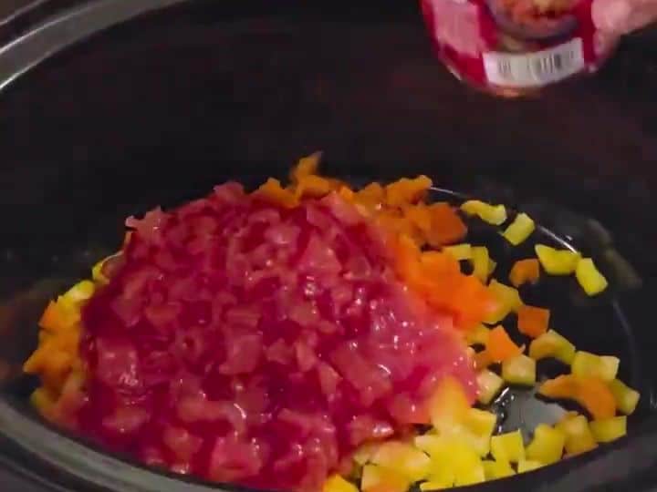 Slow Cooker Pumpkin Lentil Chili with Cinnamon and Nutmeg 4 Diced tomatoes and chopped bell peppers sit in the slow cooker as a sauce is poured in.