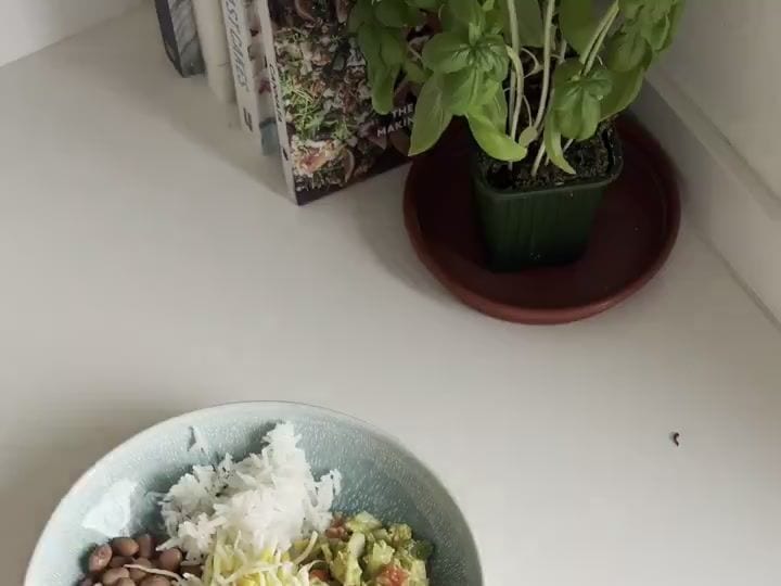 Veggie Burrito Bowls with Taco-Seasoned Guacamole 6 Two bowls are shown topped with beans, shredded cabbage, cheese, and guacamole, nearly complete.