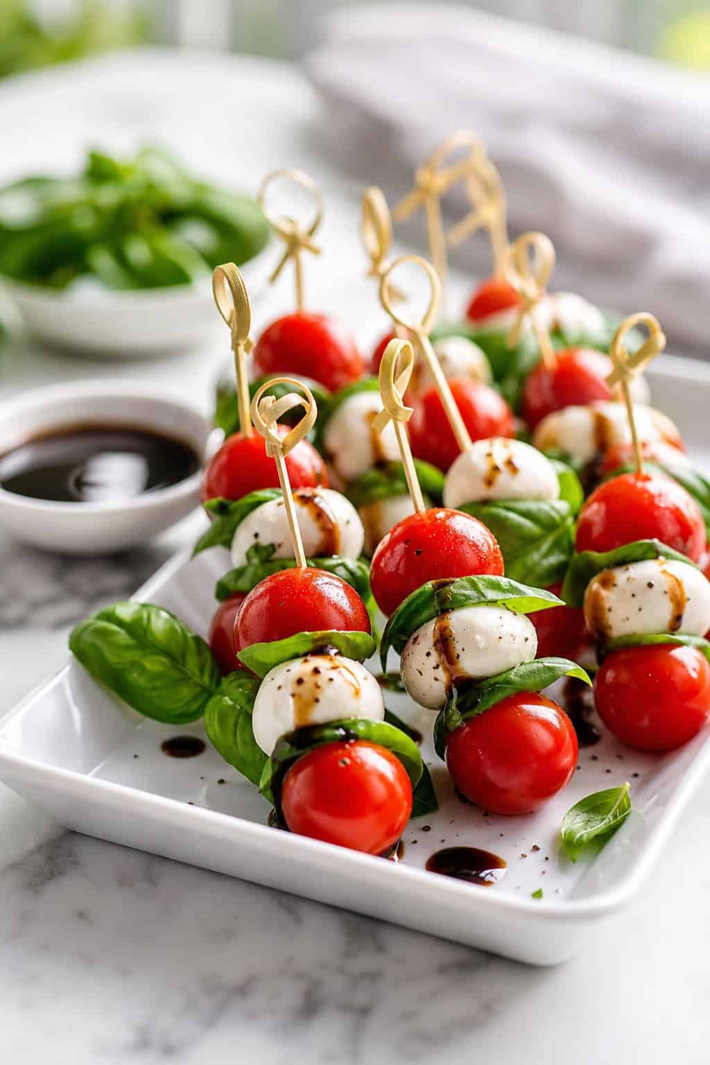 A platter of cherry tomato, basil, and vegan mozzarella skewers served with balsamic glaze.