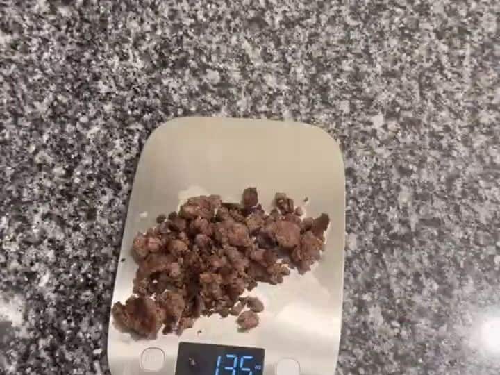 Seasoned cooked ground beef on a kitchen scale, portioned for the burger bowls.