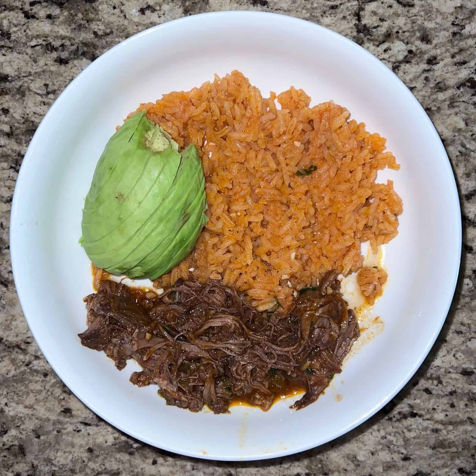 Carne asada, Mexican rice, avocado slices in a blate