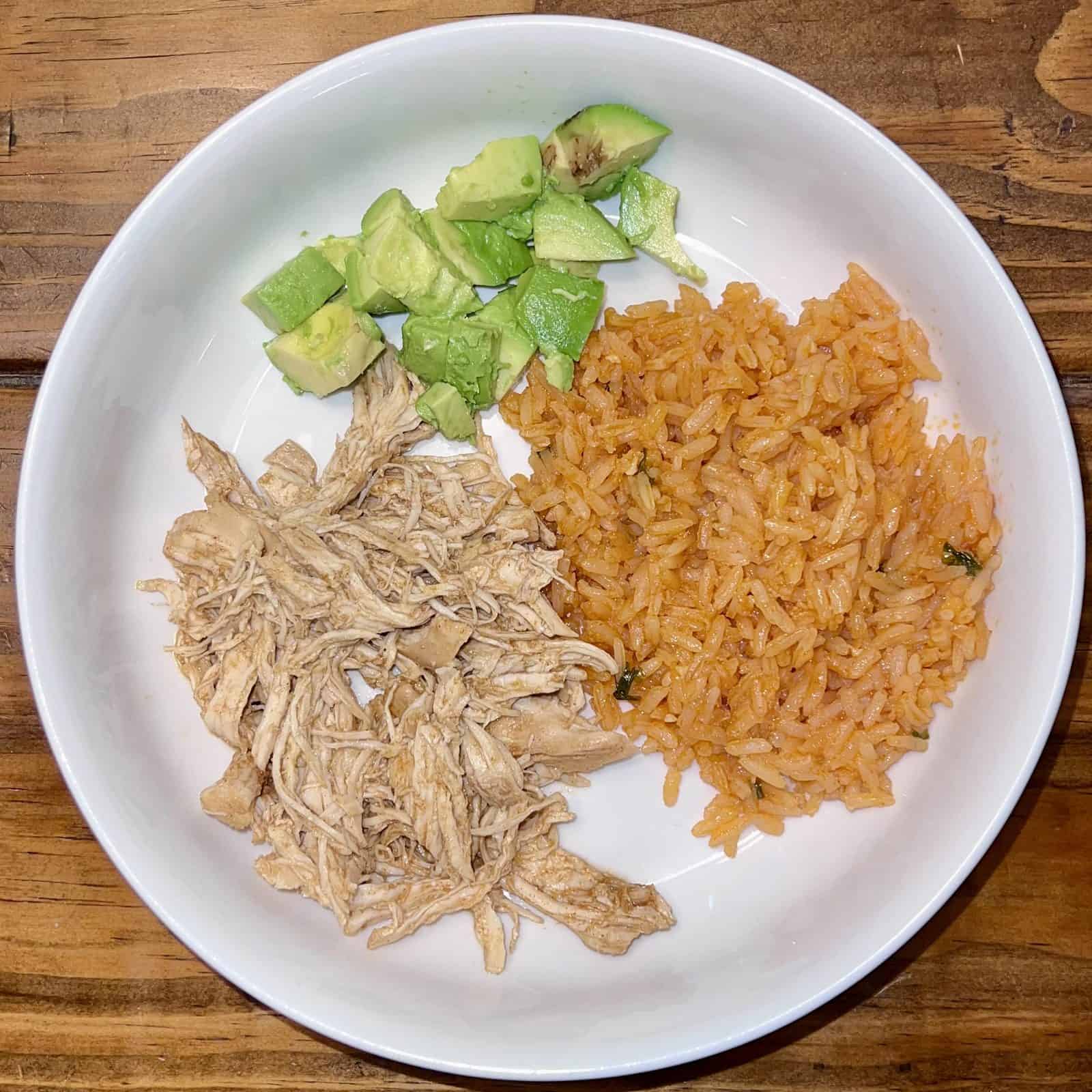 Slow Cooker Shredded Taco Chicken 2 chicken taco meat, avocado and rice in a bowl