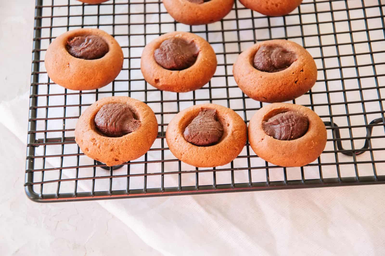 Chocolate-filled thumbprint cookies on a cooling rack