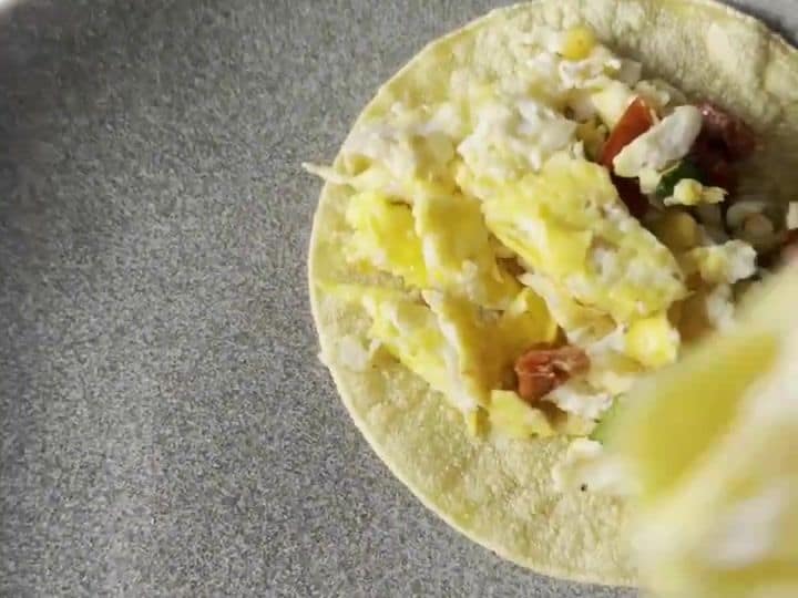 Italian Breakfast Tacos with Sun-Dried Tomatoes and Mozzarella 7 Two finished breakfast tacos filled with cheesy eggs and sun-dried tomatoes on a gray plate.