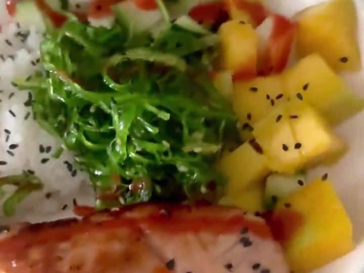 Sweet and Spicy Salmon Bowl Gets Its Crunch from Mango and Cucumber 7 A finished bowl with rice, cucumber, mango, seaweed, sesame seeds and a sriracha-topped salmon fillet.