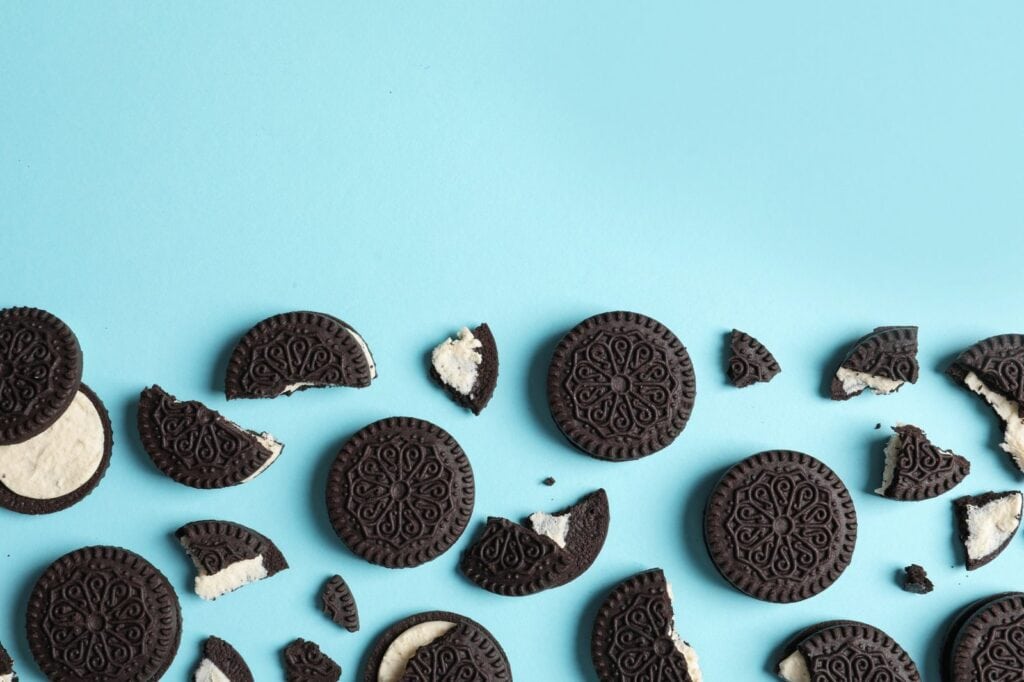 Oreo sandwich cookies, whole and broken, on a blue background