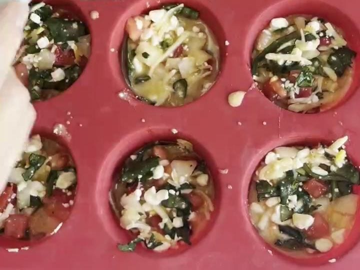 Cottage Cheese Veggie Egg Bites with a Potato Crust 6 A metal bowl is pouring the veggie and cottage cheese egg mixture over potato crusts in the red muffin tray.