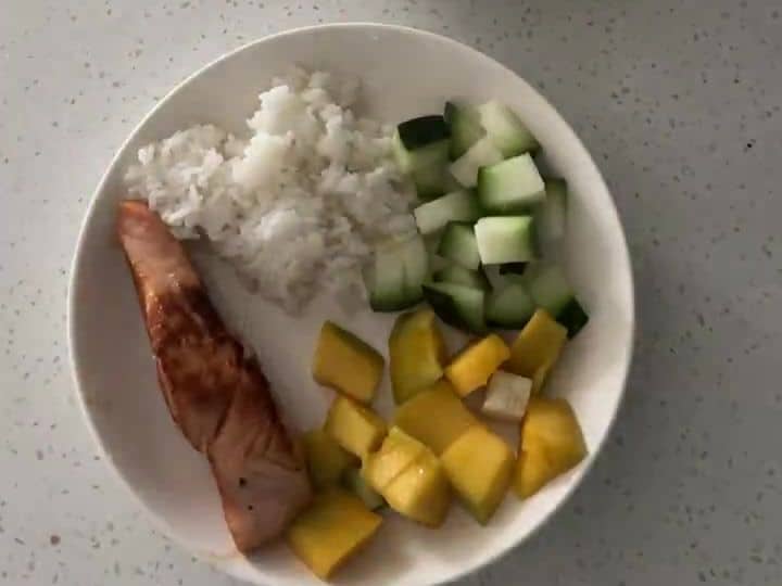 Sweet and Spicy Salmon Bowl Gets Its Crunch from Mango and Cucumber 6 A seared salmon fillet rests on top of rice next to diced mango and cucumber in a white bowl.